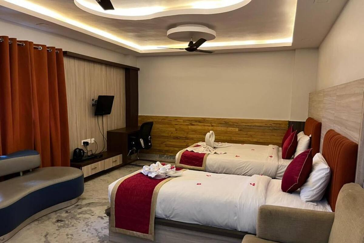 A hotel room with two beds, a seating area, a TV, and a ceiling fan.