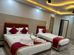 Ein Hotelzimmer mit zwei Betten, jeweils mit rotem Kopfteil, weißer Bettwäsche und dekorativen Schwanenkissen.