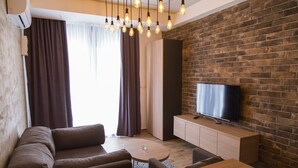 Una sala de estar moderna con pared de ladrillo, televisor de pantalla plana, sofá, mesa de centro y lámpara colgante.