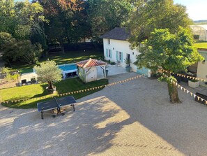 Un patio con piscina, zona de estar cubierta y pérgola.