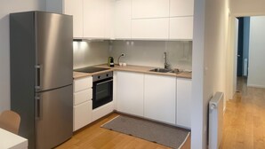 Eine moderne Küche mit weißen Schränken, einem Edelstahlkühlschrank, einem Einbauofen und einer Holz Arbeitsplatte.