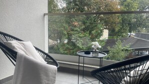 Ein Balkon mit einem Stuhl, einem kleinen Tisch und einer Blumenvase.