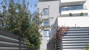 Ein schmaler Weg führt zu einem modernen Gebäude mit flachem Dach und großen Fenstern.