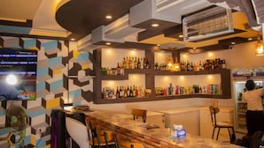 A bar area with a counter, chairs, and shelves of bottles. - Hotel Airport View (Lungi)