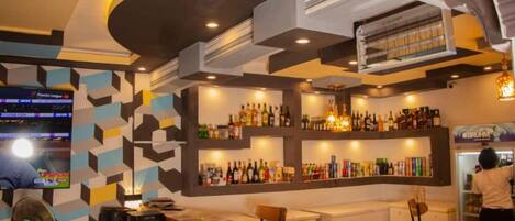 A bar area with a counter, chairs, and shelves of bottles.
