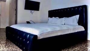 A bedroom with a large bed, a flat-screen TV mounted on the wall, and a carpeted floor. - Hotel Airport View (Lungi)