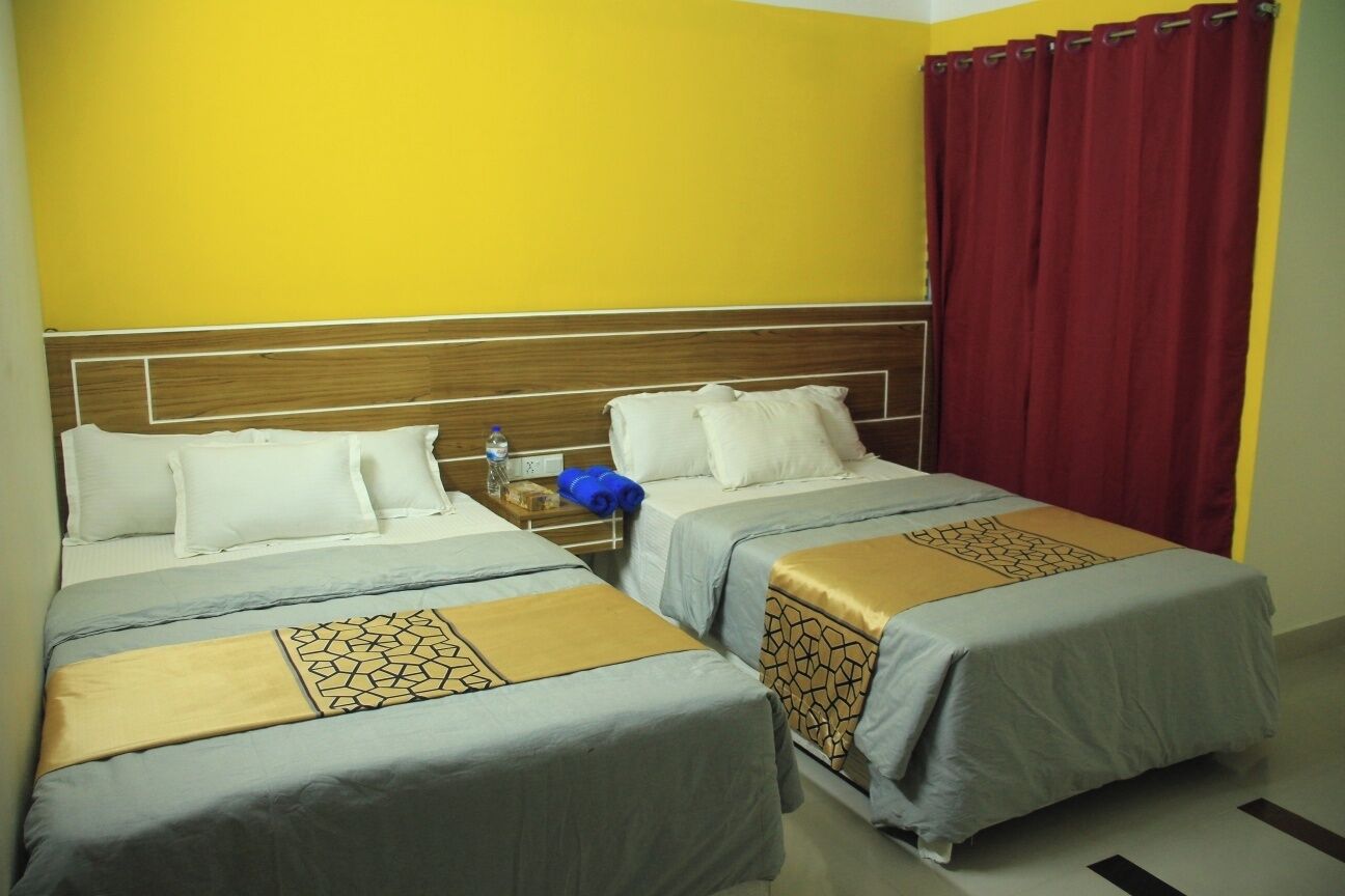 A hotel room with two beds, a wooden headboard, and a red curtain.