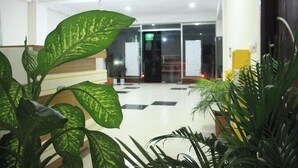A lobby with a checkered floor, potted plants, and a glass door entrance. - The Marwah Kuakata (Kalapara)
