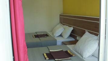 Habitación de hotel con dos camas, cabecero de madera y pared de acento amarilla.