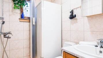 A bathroom with a wooden ceiling, a shower, a toilet, and a sink with wooden cabinets.