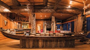 A wooden boat-shaped bar area with seating and a stone wall backdrop. - Oivangin Lomakartano (Kuusamo)