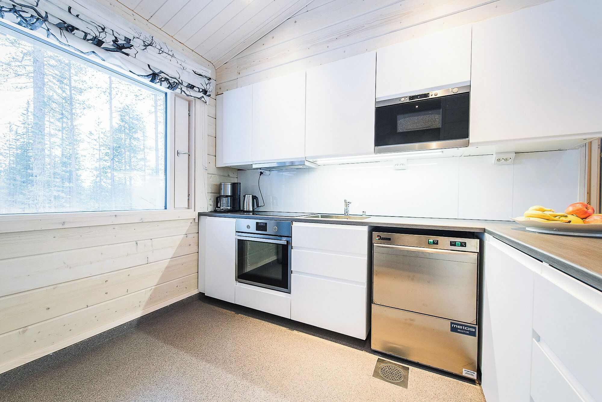 Una cucina moderna con mobili bianchi, una lavastoviglie in acciaio inossidabile e un forno integrato.