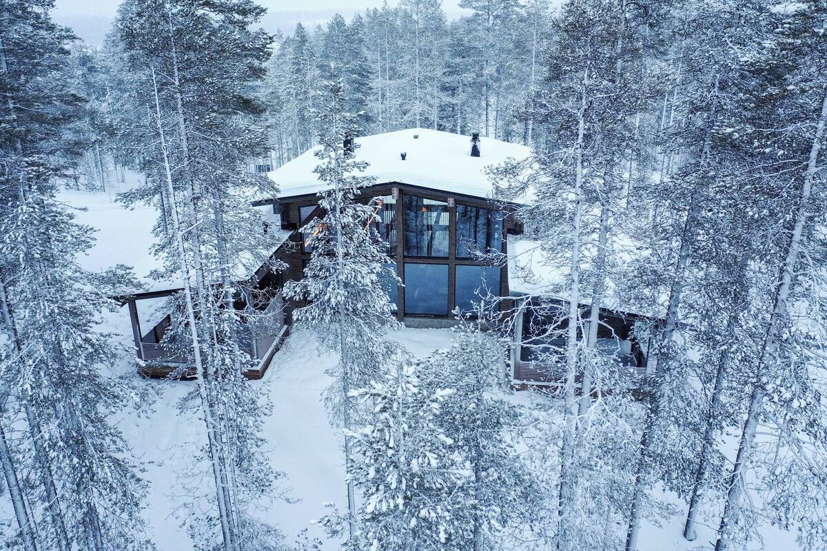 Uma cabana de madeira rodeada por árvores cobertas de neve.