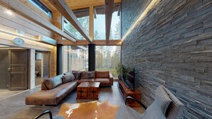 A modern interior with a wooden ceiling, stone wall, and a leather sofa set. - Oivangin Lomakartano (Kuusamo)