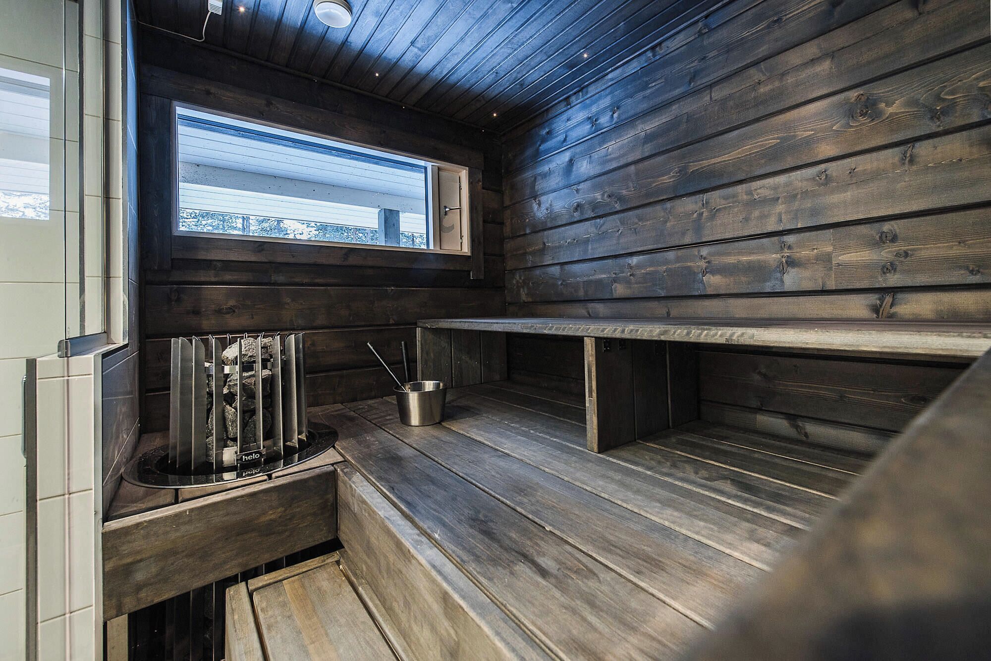 A compact kitchen with wooden walls, a window with a view, and a built-in sink with utensils.