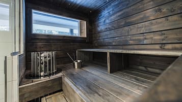 A compact kitchen with wooden walls, a window with a view, and a built-in sink with utensils.
