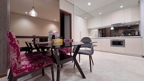 A modern dining area with a glass table, patterned chairs, and pendant lighting. - Soho Suites KLCC (Kuala Lumpur)