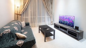 A modern living room with a sofa, a coffee table, and a TV on a stand. - Soho Suites KLCC (Kuala Lumpur)
