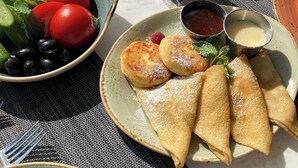 Una tavola imbandita con diversi piatti, tra cui un'insalata, formaggio e pasticcini, con una tazza di tè e condimenti.