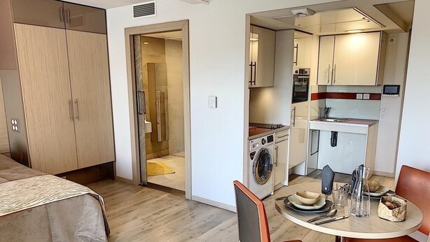 A compact hotel room with a bed, a small kitchenette, a washing machine, and a dining area with a table and chairs. - Appart One Le Cannet (Le Cannet)