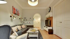 Una sala de estar con sofá, mesa de centro, televisor y un reloj en la pared.