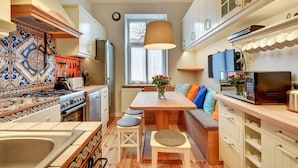Una cocina compacta con una isla central, un área de comedor con sofá y un gran ventanal que proporciona luz natural.