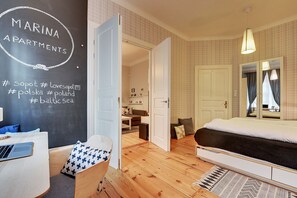 Ett sovrum med en stor säng, ett skrivbord med en bärbar dator, en stol och en vägg med text på.