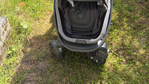A stroller parked on grass with a handlebar and a canopy.