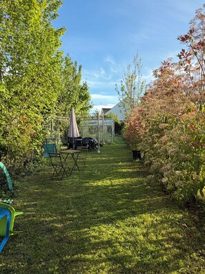 A backyard with a greenhouse, a table, and chairs.