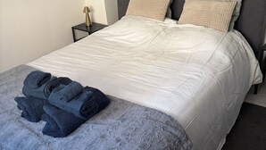 A neatly made bed with a white duvet, two pillows, and a folded blanket on the side.