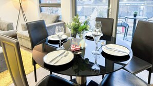 A dining table set for four with a city view through large windows. - 3-Bed Hoxton Flat w/ Private Balcony & Lift access near Shoreditch , Old Street (London)