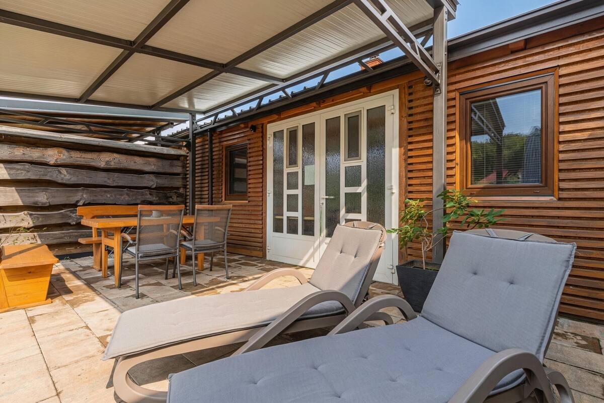 Une cabane en bois dotée d’un patio comprenant des chaises longues, une table et des chaises.