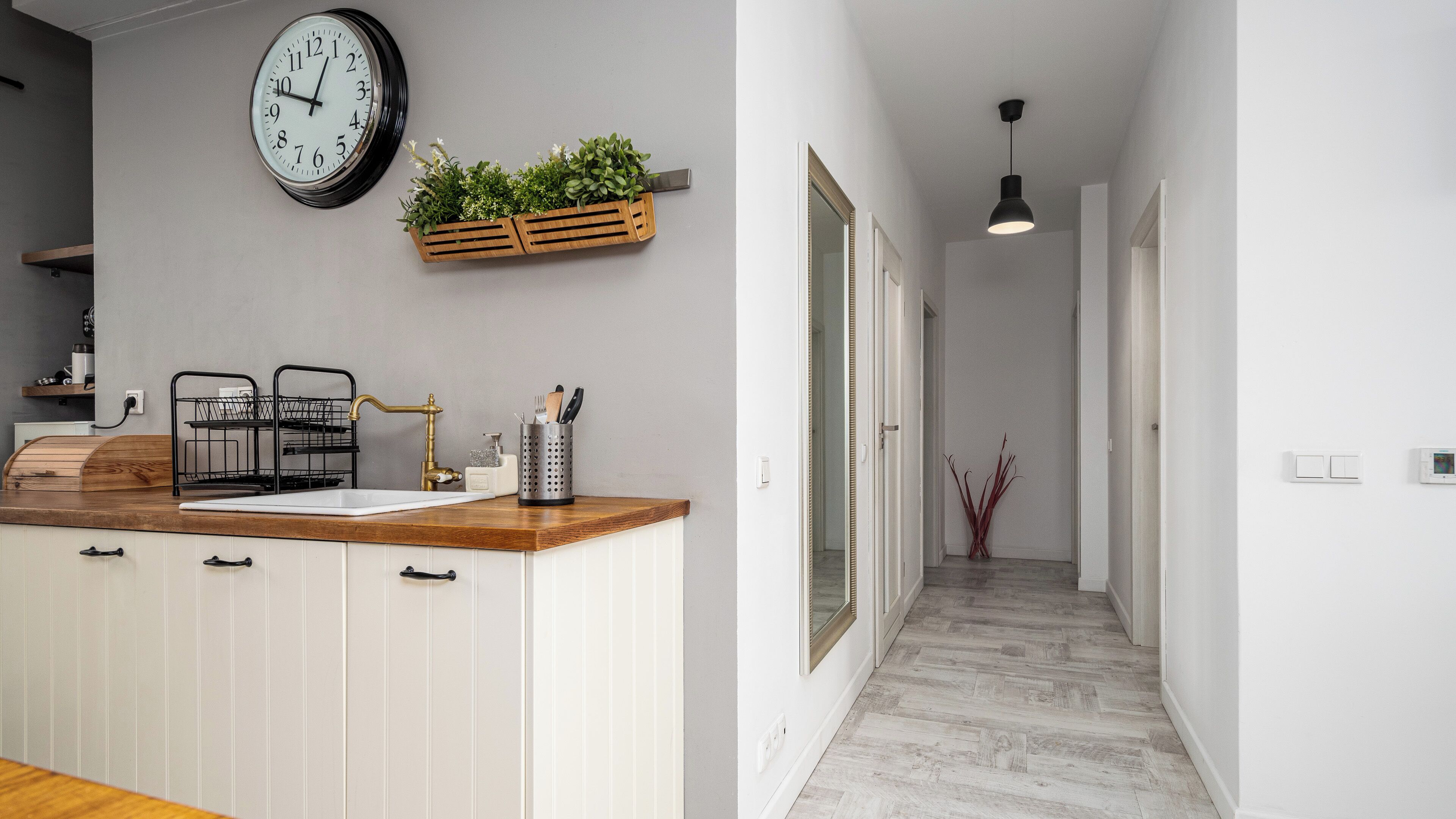 Una cocina moderna con encimera de madera, un lavabo y un reloj en la pared.