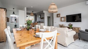 Ein moderner Essbereich mit einem Holztisch, weißen Stühlen und einer gewobenen Pendelleuchte.