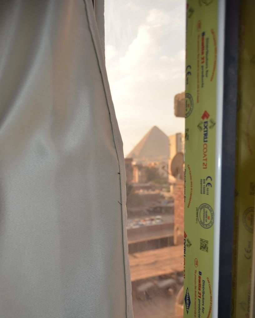 Una ventana con vista a una pirámide y materiales de construcción.