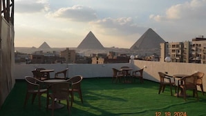 A rooftop terrace with outdoor seating and views of the pyramids. - Pyramids Terrace Hostel (Giza)
