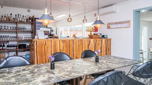Un restaurante con una larga mesa de mármol, sillas de malla metálica negra y lámparas colgantes.