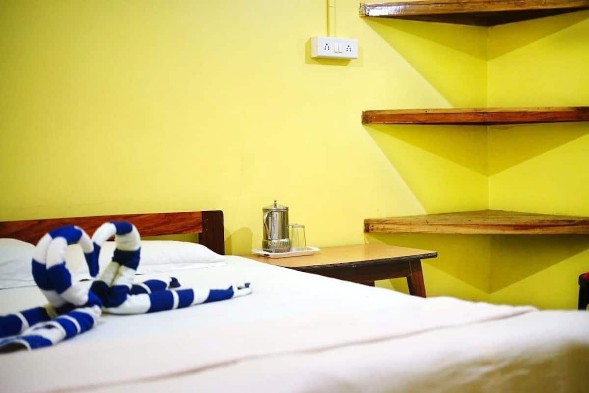 Een hotelkamer met een bed, een nachtkastje met een waterkoker, en een stopcontact.
