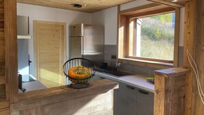 A modern kitchen with wooden beams, a large window, and a pumpkin on the counter.