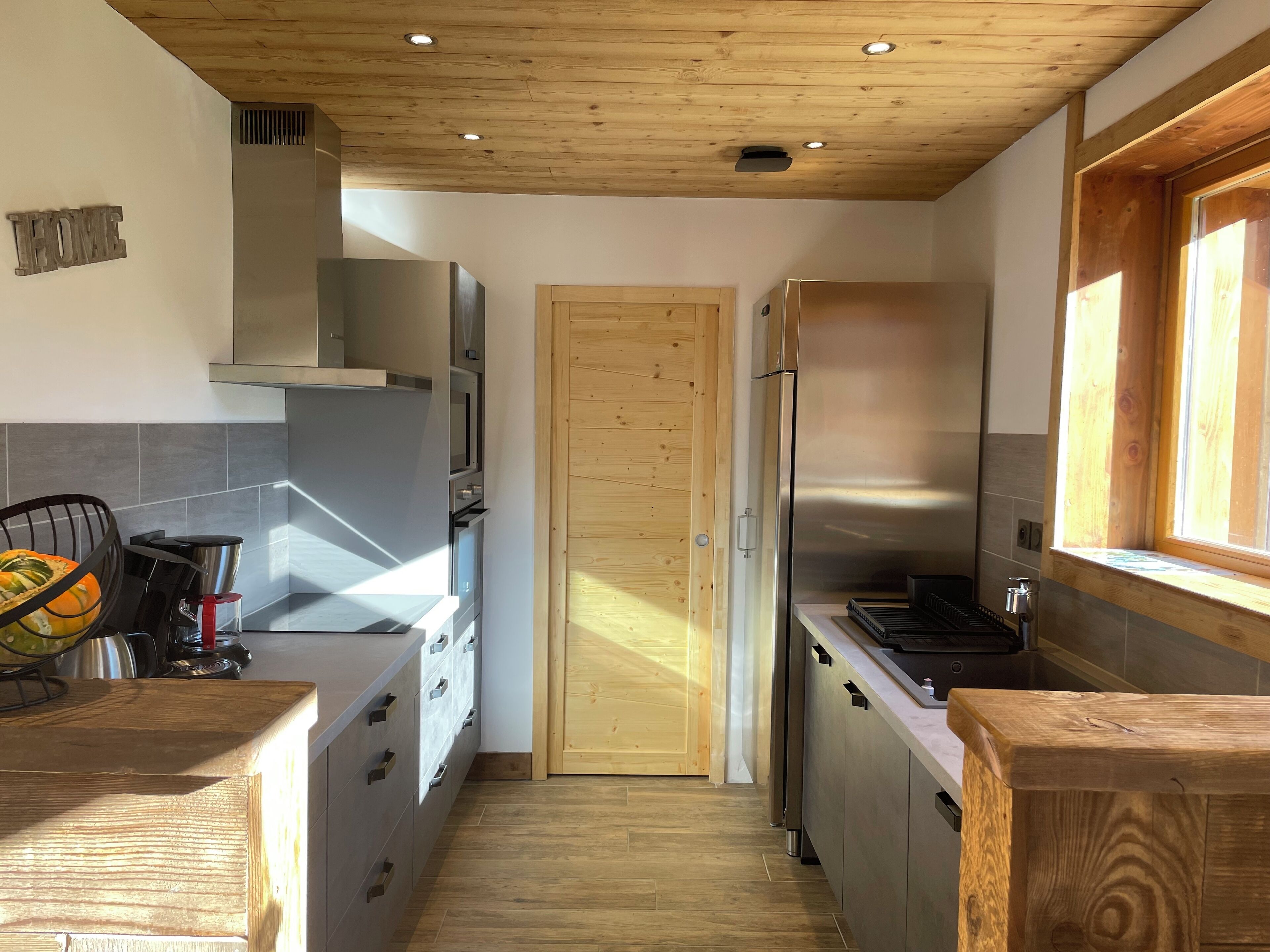 Une cuisine moderne avec des armoires en bois, des appareils électroménagers en acier inoxydable et un plafond en bois.