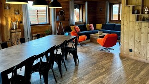 A wooden interior with a dining area, a sofa, and a bookshelf.