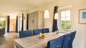 A dining area with a wooden table, blue chairs, and a fruit bowl. - Summio Duynparc De Heeren van 's-gravensande ('s-Gravenzande)