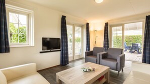 A modern living room with a flat-screen TV, two grey armchairs, a wooden coffee table, and a white sofa. - Summio Duynparc De Heeren van 's-gravensande ('s-Gravenzande)