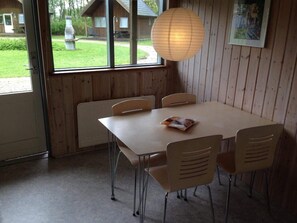 A dining area with a table and chairs, a hanging light fixture, and a view of the outside. - 4 Person Holiday Park Home in Jelling (Jelling)