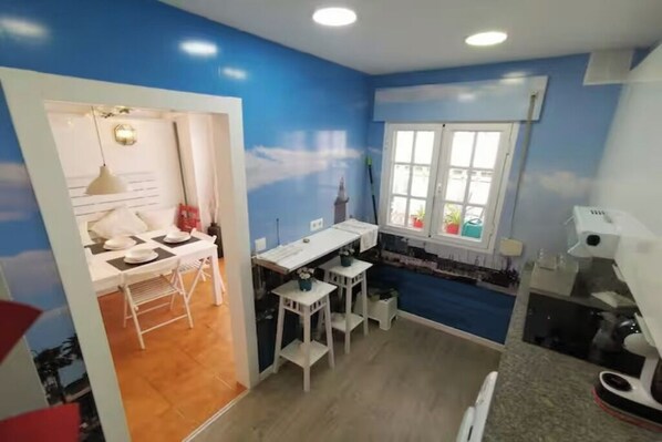 A compact kitchen with a window, a dining area with a table and chairs, and a kitchenette with a microwave.