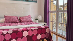 Une chambre  à coucher avec un lit, une fenêtre avec des rideaux, une plante en pot et un tableau accroché au mur.