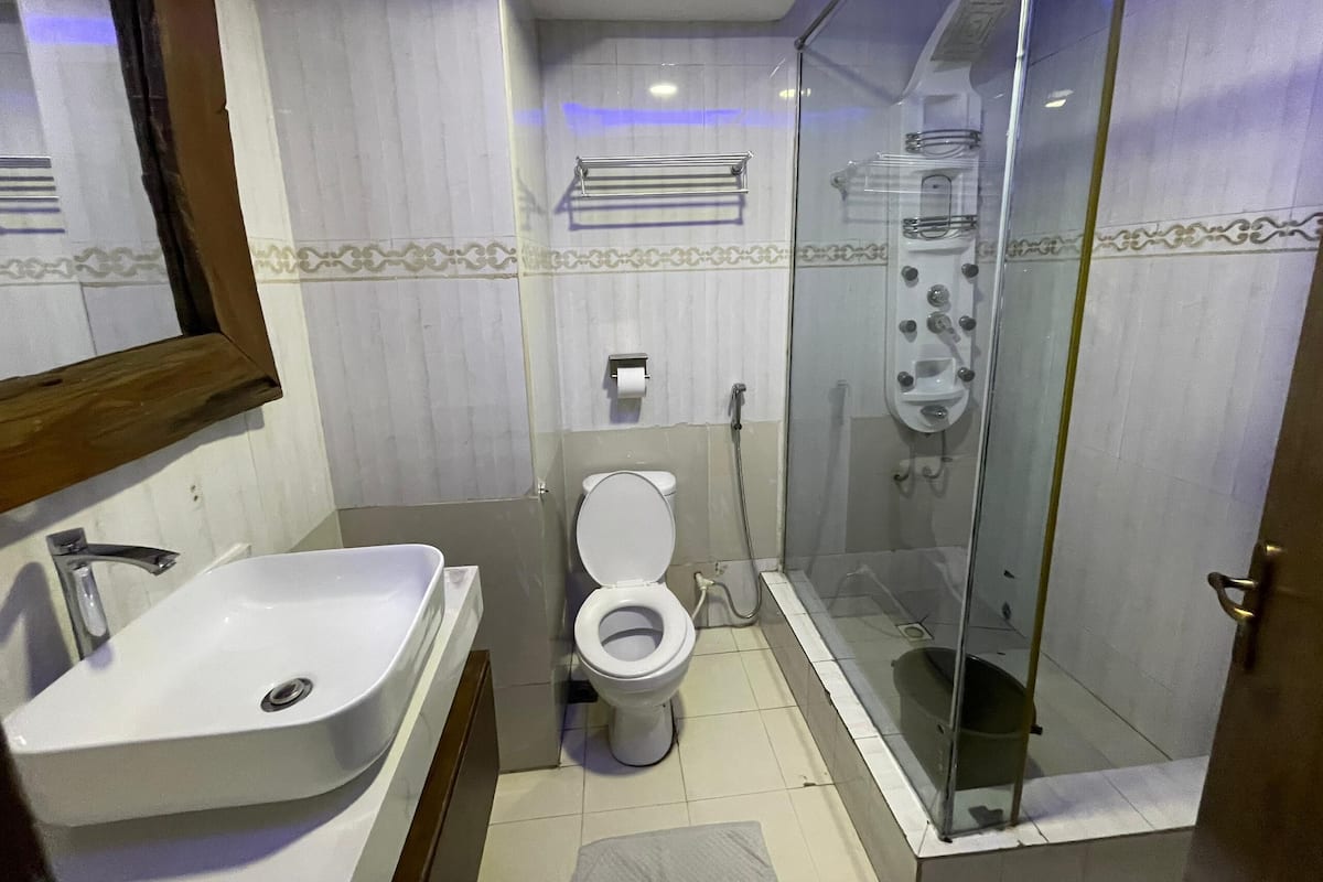 A bathroom with a sink, toilet, and glass-enclosed shower.