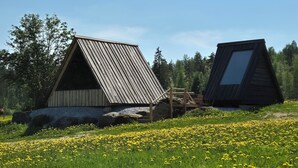 Zwei Holzhütten mit geneigten Dächern in einer natürlichen Umgebung, mit einem Feld voller gelber Blumen.
