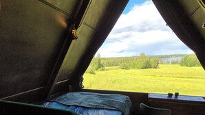 Ein Zimmer mit Bett, Stuhl und Blick auf ein grünes Feld durch ein Fenster.