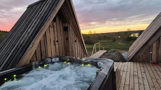 Ein Whirlpool mit Holzterrasse und Blick auf einen Sonnenuntergang.